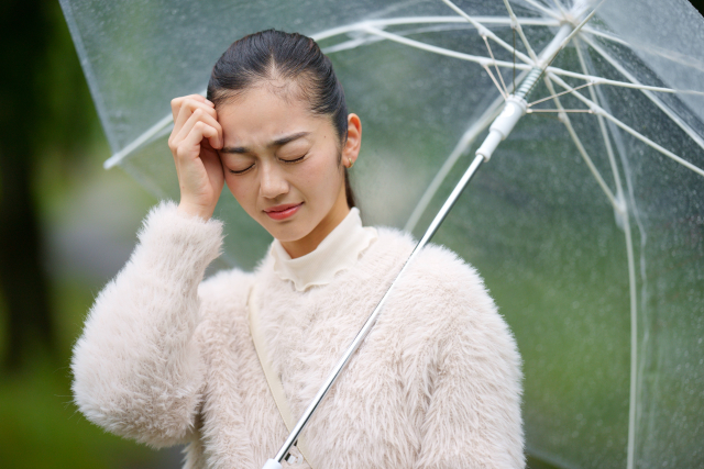 雨で頭痛で悩む女性